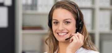 Eine junge Frau, die in die Kamera lächelt und ein Headset auf dem Kopf hat