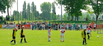 Mehrere Kinder einer Kinder-Fußballmanschaft spielen auf einer Wiese Fußball
